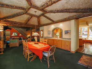 Dining area with warm materials, log accents, woodwork, kitchen tile floors