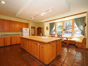 Large kitchen featuring terra cotta floors, wooden cabinets, and Southern breakfast nook sunlight