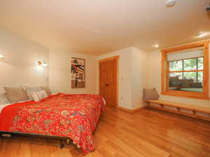 Basement primary suite with wood flooring and a window bench