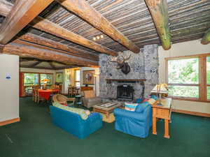 Family room featuring large stone fireplace and log ceiling