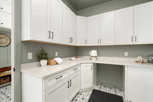 Interior space featuring built in desk, white cabinetry, and light tile floors