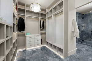 Spacious closet featuring dark tile flooring and an inviting chandelier