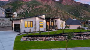 View of front of home featuring a garage, a mountain view, and a lawn