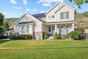 Craftsman-style home with a front lawn, a mountain view, and solar panels