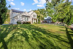 View of front of house with a front yard, a garage, and solar panels