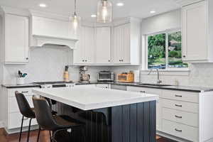 Kitchen with dark hardwood / wood-style floors, a center island, sink, and backsplash