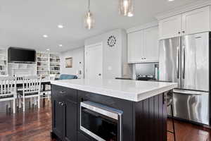 Kitchen featuring white cabinets, dark wood-type flooring, appliances with stainless steel finishes, and decorative light fixtures