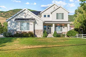 View of front of home with a front lawn, a mountain view, and a porch