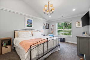 Carpeted bedroom with a chandelier and lofted ceiling