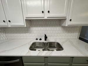 Kitchen with green cabinets, white cabinetry, sink, and decorative backsplash