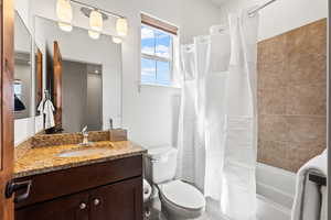 Full bathroom with shower / bath combination with curtain, oversized vanity, and toilet