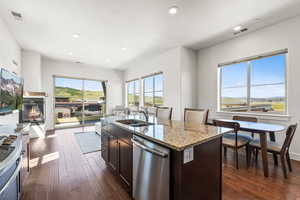 Kitchen featuring white range, dark wood-type flooring, stainless steel dishwasher, a kitchen island with sink, and dark brown cabinetry