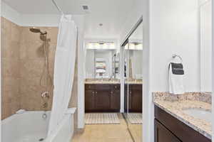 Bathroom with shower / bathtub combination with curtain, tile flooring, and vanity