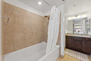 Bathroom with tile flooring, shower / bath combination with curtain, and vanity with extensive cabinet space