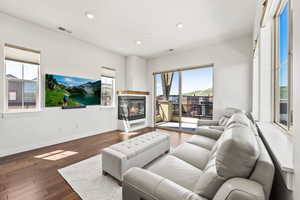 Living room with a multi sided fireplace, a healthy amount of sunlight, and hardwood / wood-style flooring