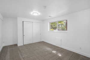 Unfurnished bedroom featuring a closet and dark colored carpet