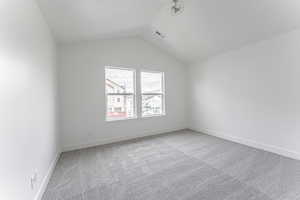 Empty room with lofted ceiling and carpet