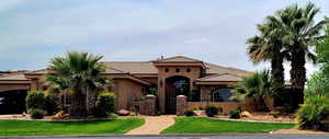 Mediterranean style house featuring mature landscaping, courtyard entrance and front lawn.