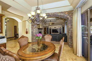Dining space featuring, marble floor, a tray ceiling, arched stone walkway