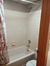 Bathroom featuring toilet and shower / bath combo with shower curtain