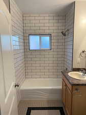 Bathroom featuring tile patterned floors, tiled shower / bath combo, and vanity