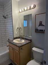 Full bathroom with toilet, vanity, tile patterned floors, and tiled shower / bath combo