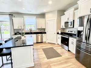 Kitchen featuring a center island, light hardwood / wood-style flooring, stainless steel appliances, white cabinets, and sink