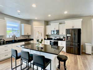 Kitchen with appliances with stainless steel finishes, light hardwood / wood-style floors, a center island, and sink