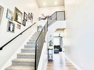 Staircase featuring a high ceiling, ceiling fan, and wood-type flooring