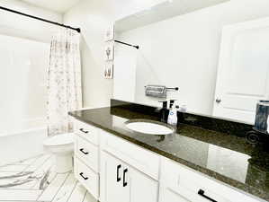 Full bathroom with oversized vanity, toilet, tile floors, and shower / tub combo with curtain