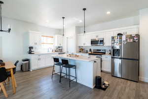 Kitchen with white cabinetry, granite counter tops, a kitchen island, and stainless steel appliances