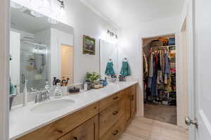 Bathroom with tile patterned flooring, double vanity, and a shower