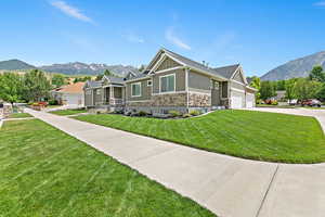 Craftsman house with a garage, a front lawn, and a mountain view