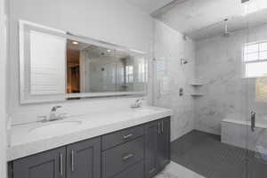 Bathroom with vanity with extensive cabinet space, walk in shower, double sink, and tile floors