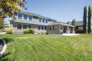 Back of house with a lawn and a patio