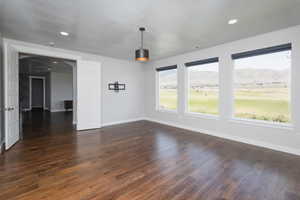 Unfurnished living room with a mountain view and dark wood-type flooring