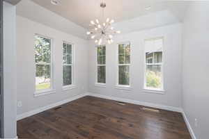 Spare room featuring a notable chandelier, hardwood / wood-style flooring, and a wealth of natural light