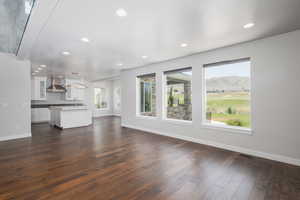 Unfurnished living room featuring dark hardwood / wood-style floors, sink, and a wealth of natural light