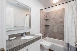 Full bathroom featuring toilet, shower / bathtub combination with curtain, and vanity