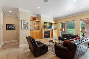 Tiled living room with built in features, a tiled fireplace, and ornamental molding