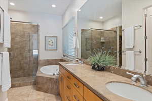 Bathroom featuring separate shower and tub, dual sinks, tile floors, and oversized vanity