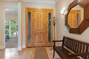 Entryway with carpet floors and crown molding