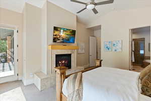 Carpeted bedroom with access to outside, a tiled fireplace, ceiling fan, and multiple windows