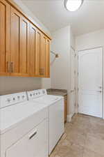 Washroom with cabinets, light tile floors, and washing machine and clothes dryer