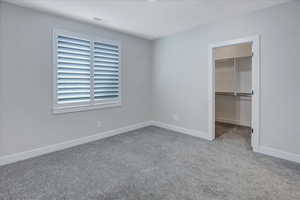 Unfurnished bedroom with a walk in closet, a closet, and carpet