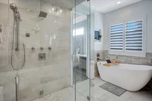 Bathroom featuring shower with separate bathtub, tile flooring, and tile walls