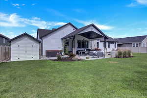 Back of property with outdoor lounge area, ceiling fan, a shed, a patio, and a lawn