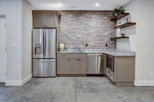 Kitchen featuring appliances with stainless steel finishes, sink, backsplash, and light stone counters