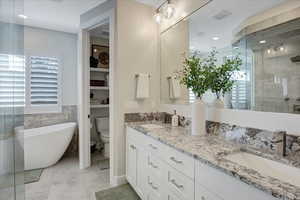 Full bathroom with tile flooring, large vanity, separate shower and tub, toilet, and dual sinks