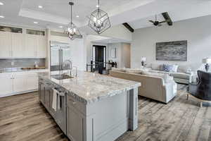 Kitchen with white cabinetry, stainless steel appliances, hardwood / wood-style flooring, a kitchen island with sink, and sink